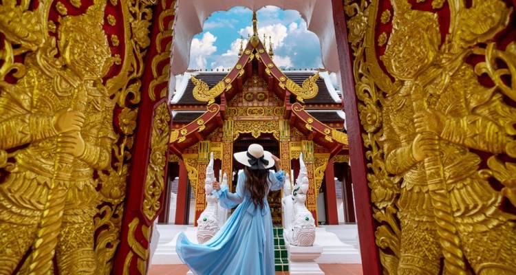 Frau in einem blauen Kleid steht im verzierten Tempeleingang.