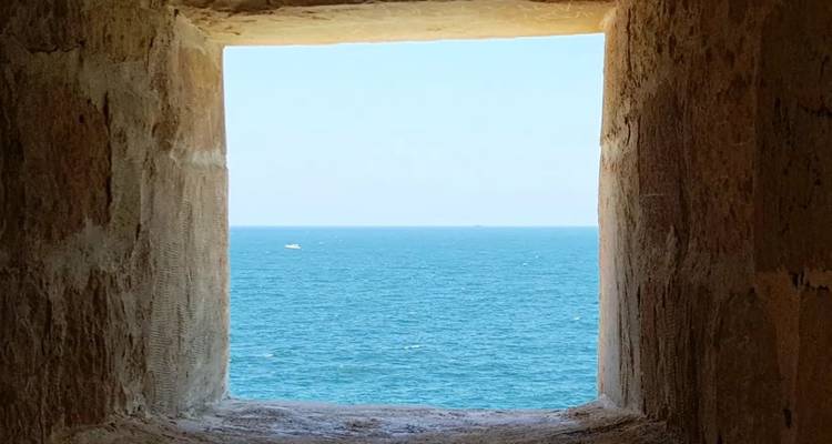 Uitzicht op de zee door een stenen raam.