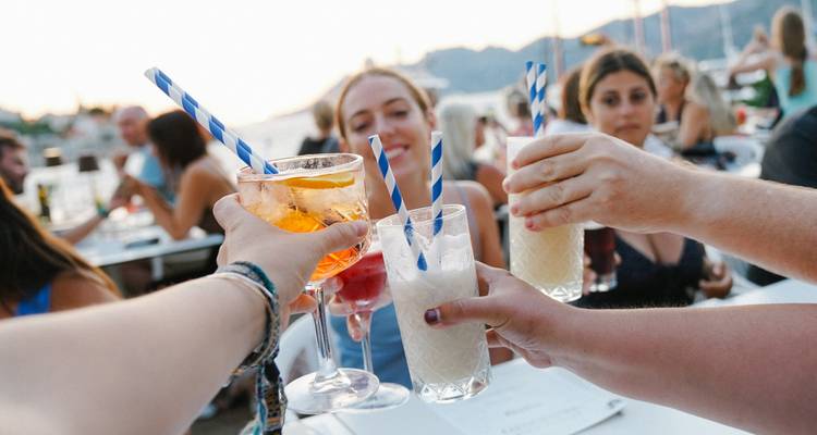 Group of people clinking glasses at an outdoor dining area.