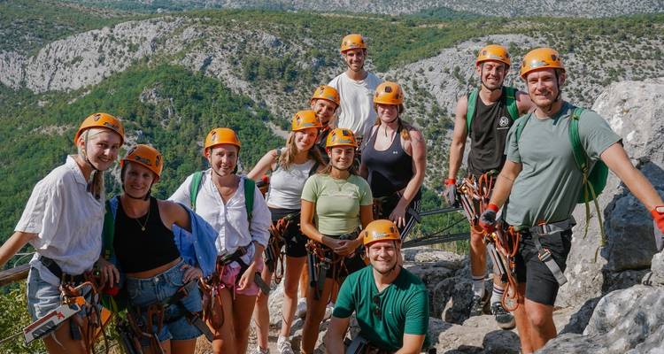 Group of people with climbing gear posing on a mountain with a scenic view.