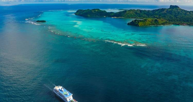 Vista aérea de un barco cerca de islas tropicales con agua azul cristalina.