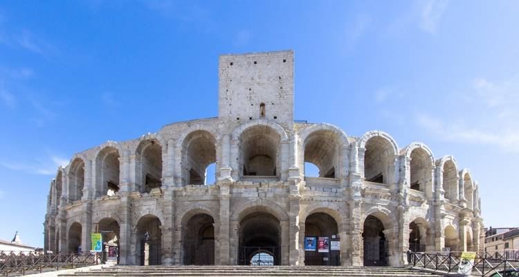 Amphithéâtre romain bien conservé à Arles se dressant fièrement contre un ciel bleu dégagé.