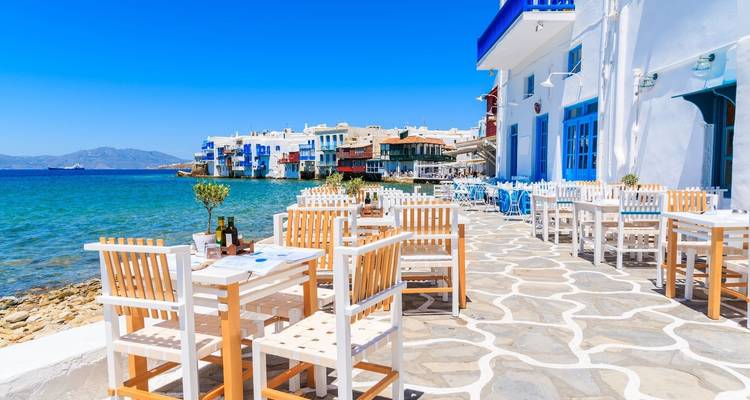 Terraza de restaurante al aire libre junto al mar con vista a la arquitectura blanca.