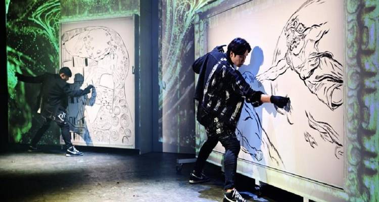 Kunstperformance mit zwei Künstlern, die auf Leinwänden in einer Bühnenszenerie malen.