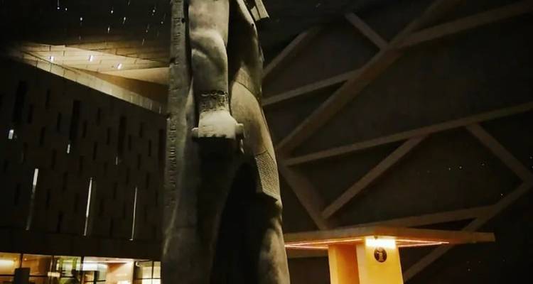 Standbeeld tegen een moderne architecturale achtergrond 's nachts.