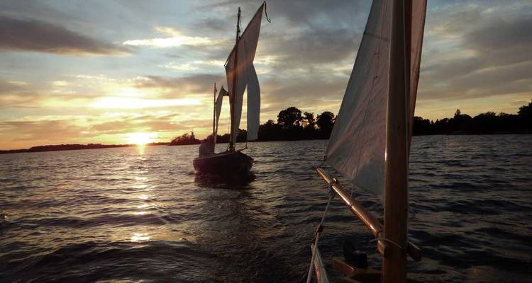 Boote, die bei Sonnenuntergang auf einem Fluss segeln.