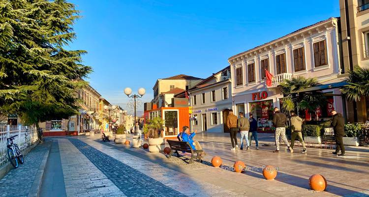Straatbeeld in een kleine stad met wandelende mensen en winkels aan beide kanten.