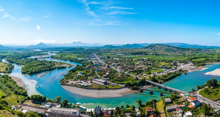 Luchtfoto van een vallei met rivieren en steden, omringd door bergen.