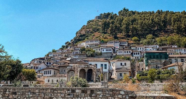 Traditionele stenen huizen op een heuvel met groen.