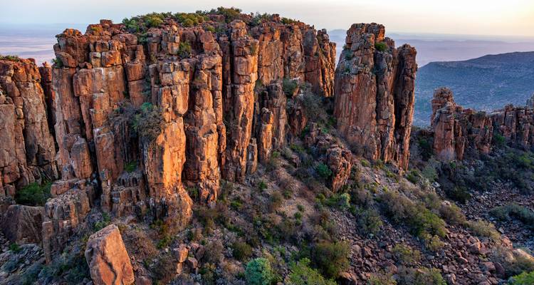 Formations de falaises rocheuses avec verdure au coucher du soleil.