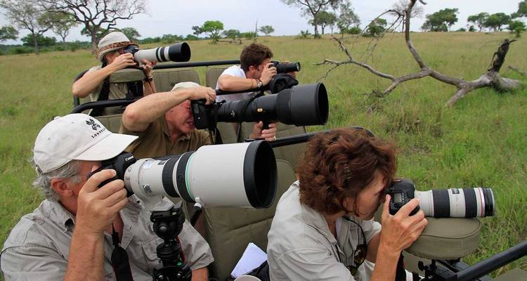Gruppe von Fotografen in einem Safari-Fahrzeug beim Fotografieren von Wildtieren.