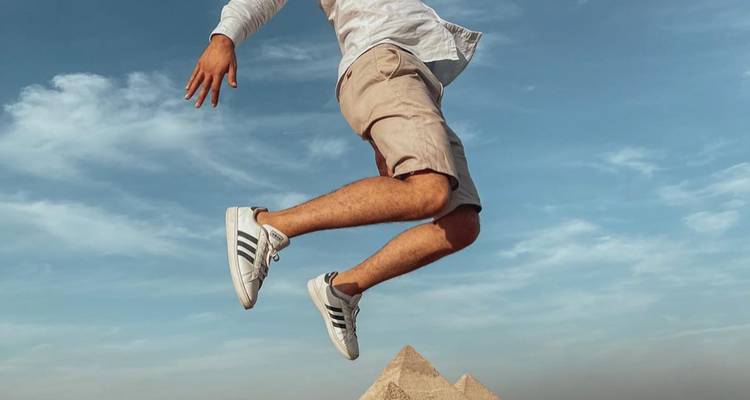 Person jumping with pyramids in the background, Cairo.