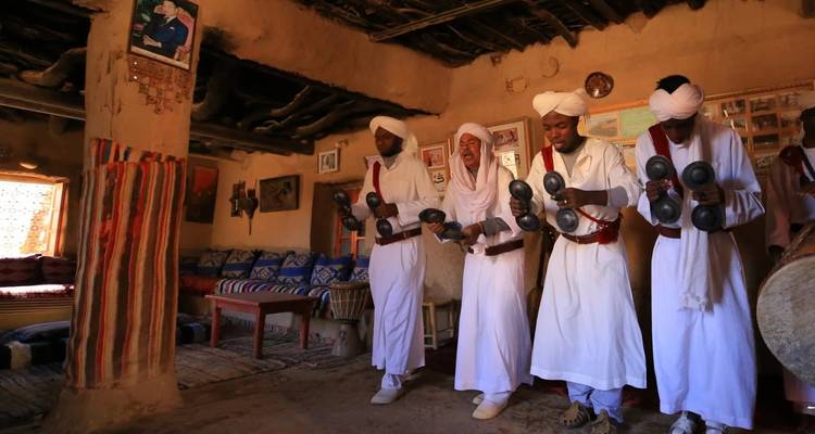 Gruppe von Menschen in traditioneller Kleidung, die drinnen Musik aufführen.
