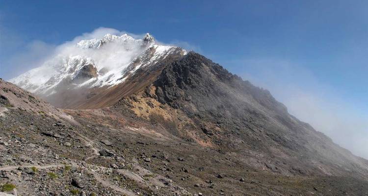 Felsgipfel mit Wolken und blauem Himmel.