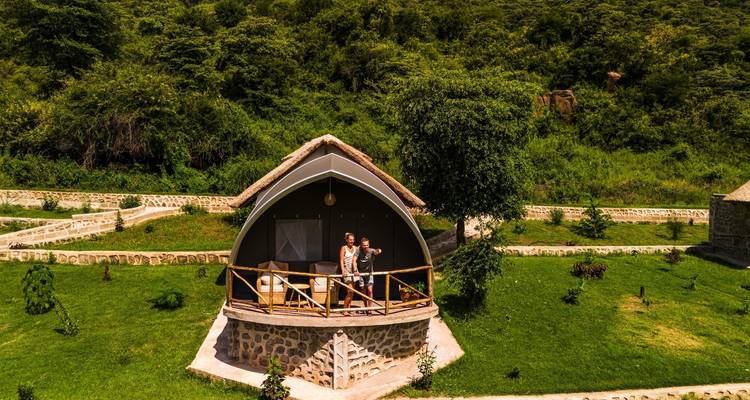 Couple debout sur le balcon d'un cottage entouré de verdure.
