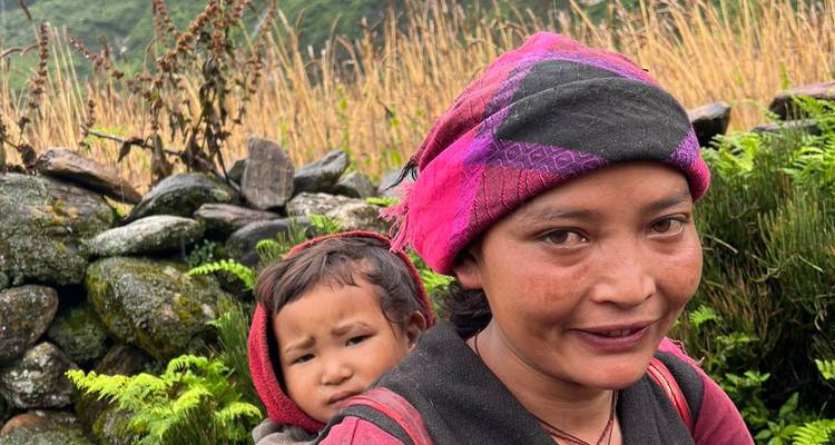 Femme portant un enfant dans un cadre rural.