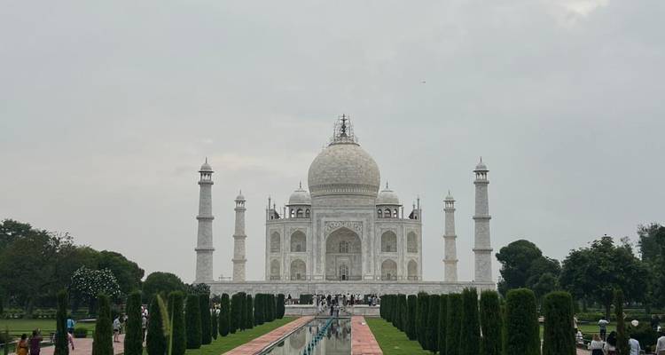 Vue large du mausolée emblématique en marbre blanc avec un jardin.