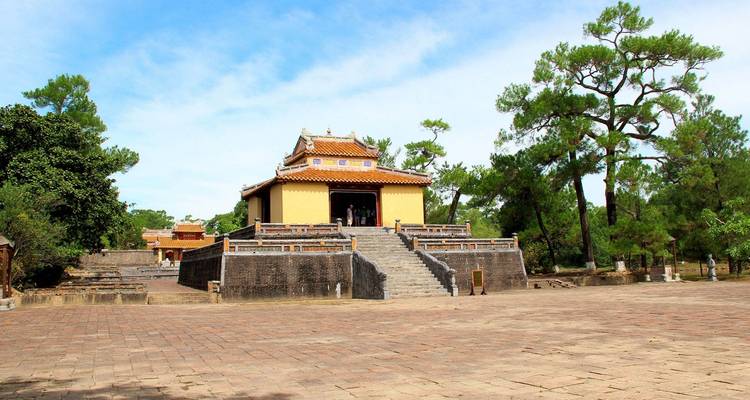 Traditionele gele Vietnamese tempel omringd door bomen.
