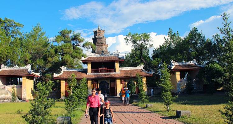 Mensen die door de poorten van een Vietnamese tempel lopen met een hoge toren op de achtergrond.
