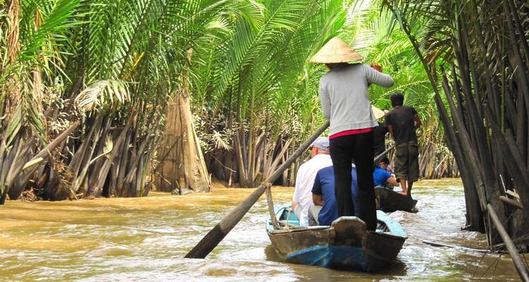 Mensen op een boot die peddelen door een junglerivier.