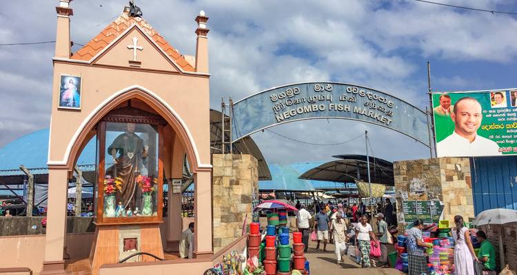 Negombo vismarkt met mensen en een lokaal heiligdom.