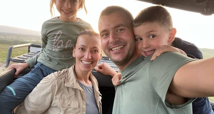 Familie posiert für ein Selfie aus einem Safari-Fahrzeug heraus.