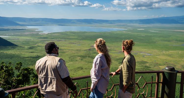 Touristen, die eine weite grüne Landschaft mit einem See überblicken.