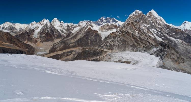 Vaste paysage enneigé avec des sommets himalayens imposants en arrière-plan.