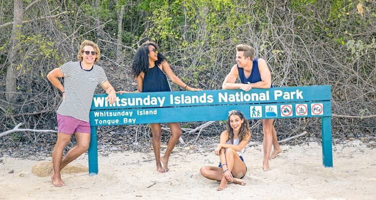 Groupe de personnes posant à côté d'un panneau du parc national des îles Whitsunday