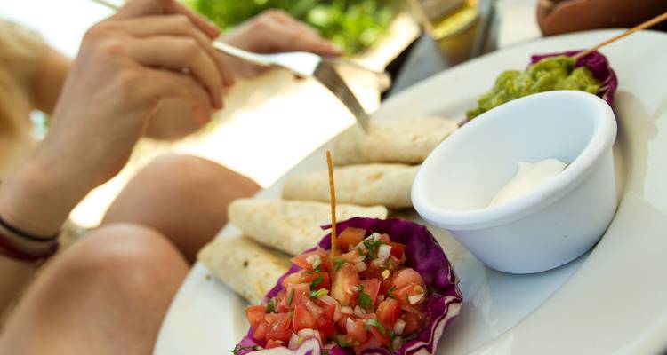 Primer plano de tortillas mexicanas con salsa fresca y salsas en una mesa soleada