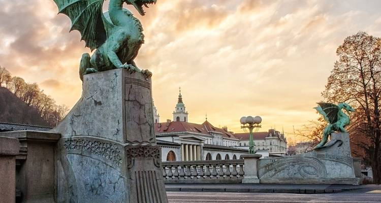Dragon sculptures on a bridge with city architecture in the background.