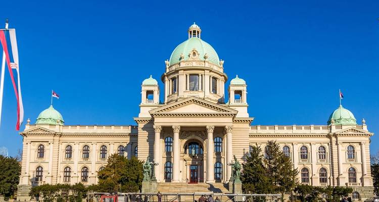 Elegantes Regierungsgebäude mit Kuppel und Flaggen an einem klaren Tag.