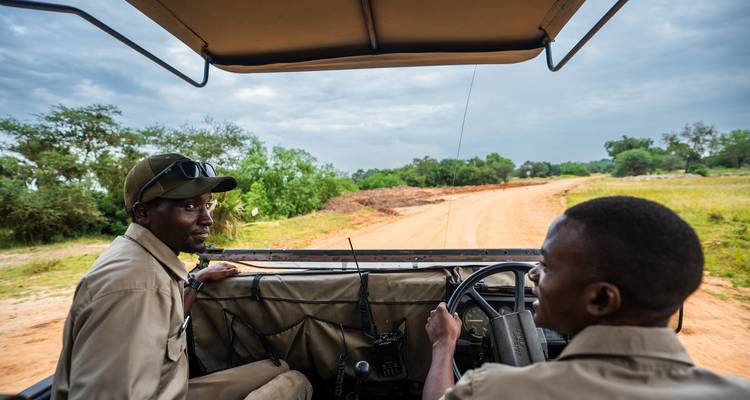 Two safari guides smiling and chatting in a vehicle.
