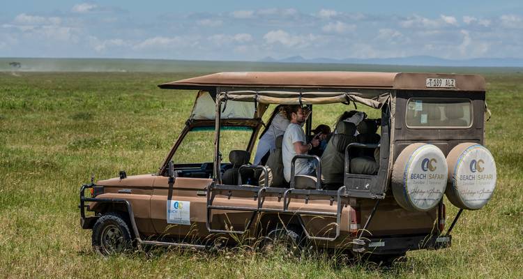 Tourists in a safari vehicle on a grassland.
