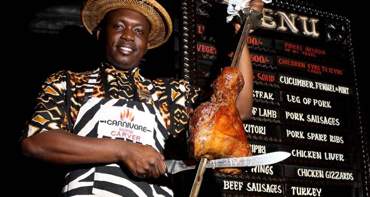 Man die een stuk geroosterd vlees vasthoudt in een restaurant.