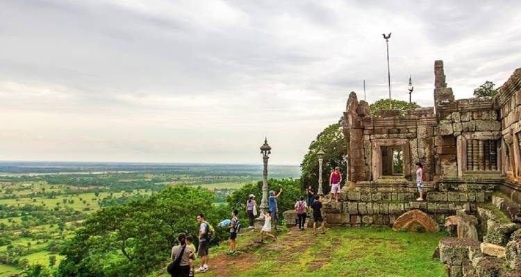 Groep toeristen die oude ruïnes verkent met uitzicht over een vallei.