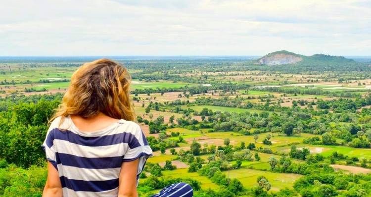 Vrouw zittend met haar rug naar de camera gericht, uitkijkend over een schilderachtig landschap.