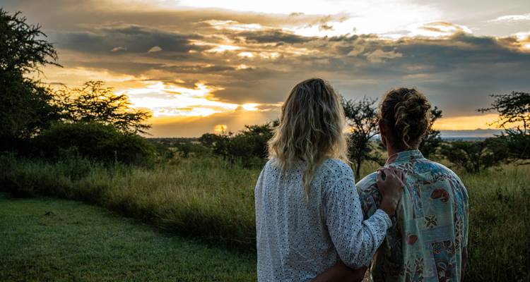 Couple admiring a sunset over the savannah landscape.