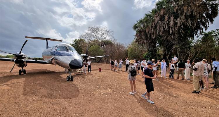 Des personnes sortant d'un avion sur une piste en terre.
