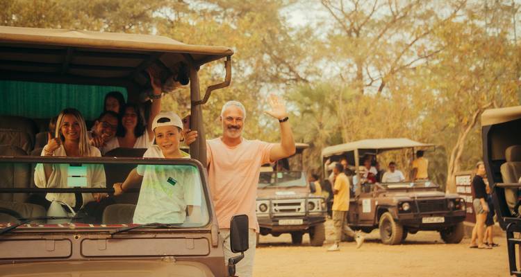 Groupe dans un véhicule de safari qui salue de la main.