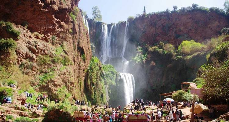 Tourists at the base of Ouzoud Falls with scenic surroundings.