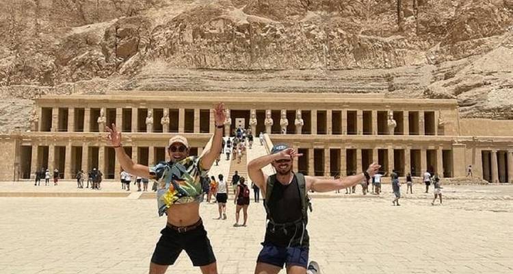 Zwei Touristen springen vor einem ägyptischen Tempel.