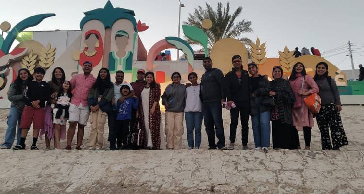 Große Gruppe posiert vor einem bunten Wandgemälde.