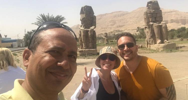 Gruppe lächelt mit großen Statuen im Hintergrund.