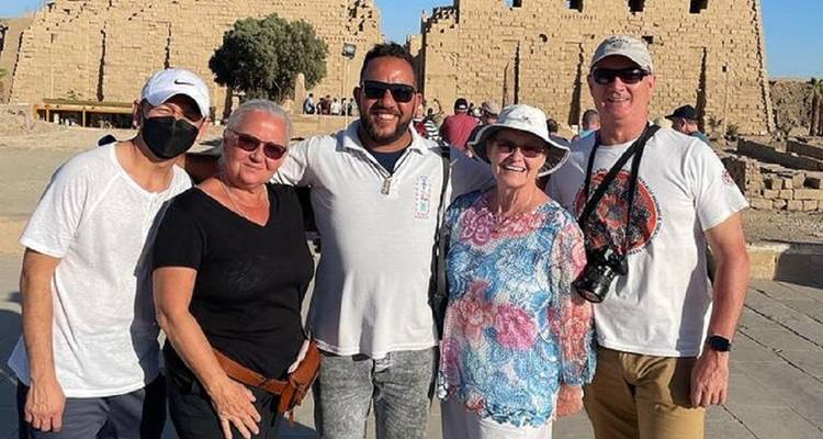 Cinco viajeros se reúnen sonriendo con ruinas soleadas and muros altos detrás de ellos.