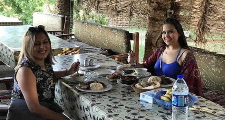 Twee vrouwen dineren in een rustieke buitenomgeving.