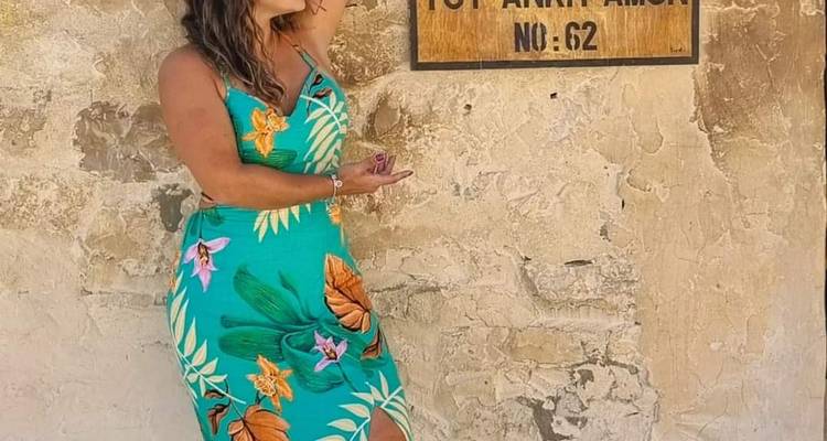 Vrouw poseert voor een bord op een stenen muur.