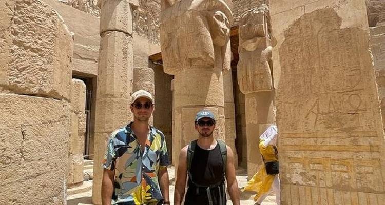 Twee mannen poseren voor oude Egyptische beelden.