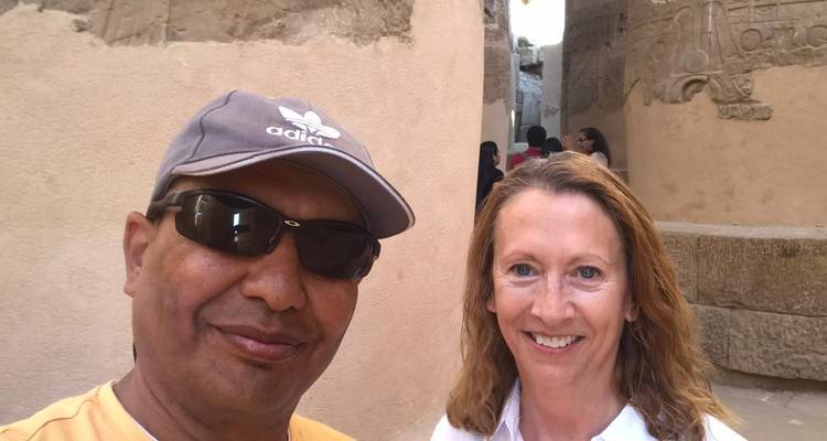 Close-up selfie van gids en reiziger naast tempelmuren en gebeeldhouwde zuilen.
