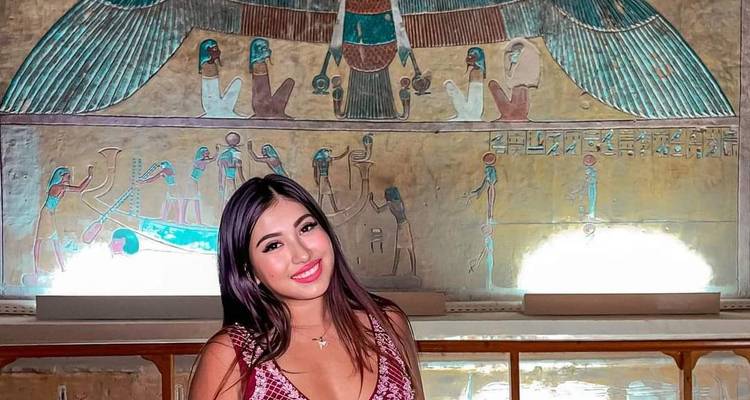 Frau lächelt vor ägyptischer Wandkunst.